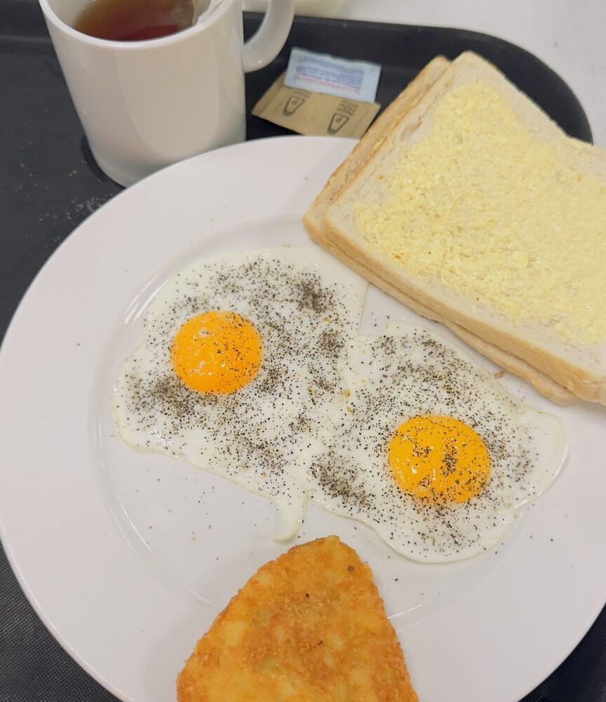 Breakfast plate with eggs, toast, a hash brown, and tea.