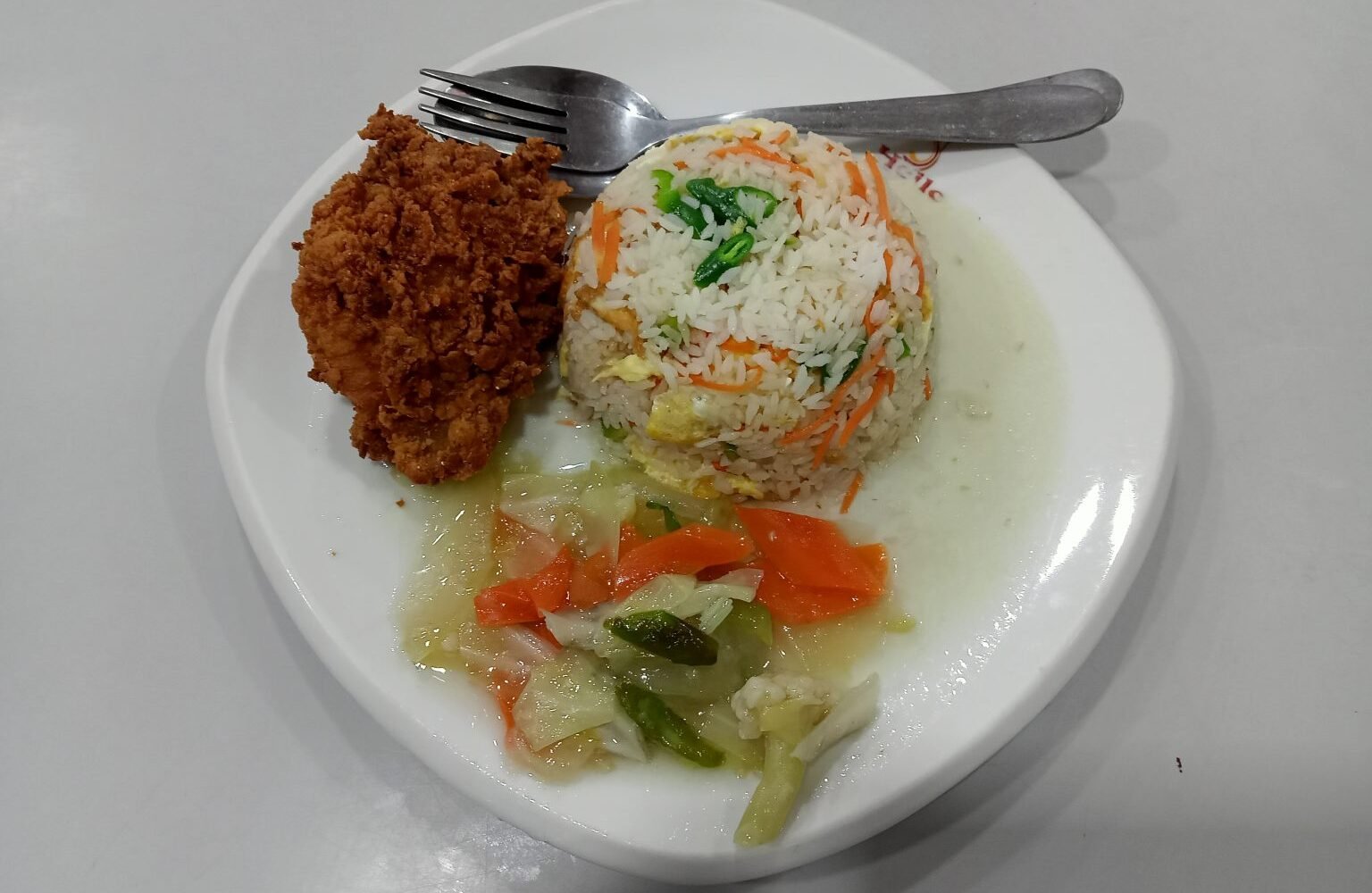 A meal of fried rice, fried chicken, and vegetables on a plate.