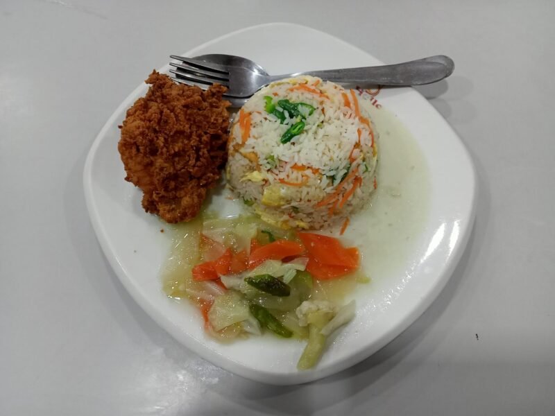 A meal of fried rice, fried chicken, and vegetables on a plate.